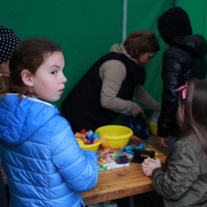 Grupka dzieci przy zielonym stoisku podczas zabawy na pikniku „Dzień Rodziny" w Grabowie.