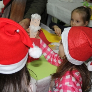 Dziewczynki w czapkach Mikołaja robią ozdoby świąteczne.