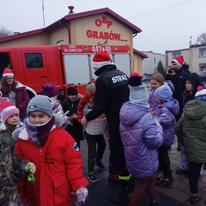 Spotkanie dzieci w czapkach Mikołaja ze strażą pożarną.