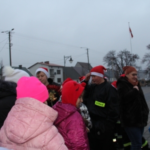 Spotkanie strażaków w czapkach Mikołaja z dziećmi.
