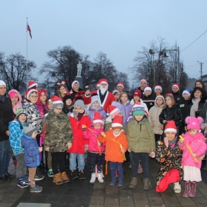 Wspólne zdjęcie pań prowadzących, Pani Dyrektor Paulina Frontczak-Pawłowskiej, dzieci w czapkach Mikołaja i pana przebranego za Świętego Mikołaja.