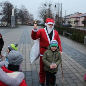 Mężczyzna przebrany za Świętego Mikołaja pozuje do zdjęcia z chłopcem i dzwonkiem w ręku.