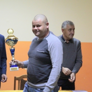 Uśmiechnięty laureat ze Związku Hodowców Gołębi Pocztowych trzyma w rękach otrzymany puchar.