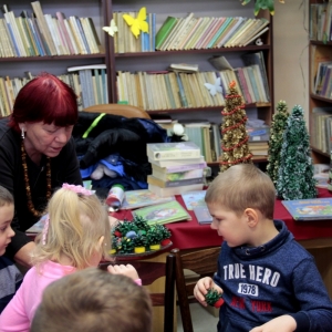 Prowadząca warsztaty pokazuje dzieciom stroiki bożonarodzeniowe.