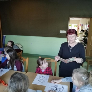 Dzieci kolorują obrazki przy stołach. 