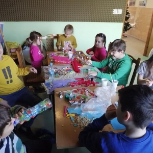 Dzieci bawią się przy stole pełnym przyborów plastycznych.