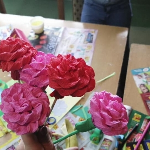 Pięć czerwonych i różowych różyczek zrobionych z krepiny.